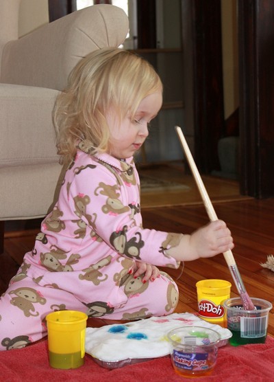 Little girl painting cake.