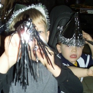 Two kids with hats and horns, celebrating New Year's Eve.