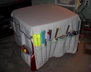 Fabric table cover with pockets for organizing craft supplies and tools.