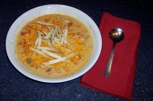 A bowl of Chicken Tortilla Soup next to a napkin and spoon.