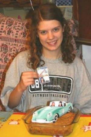 Girl holding license with cookie topped with car cutout.
