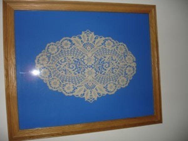 An antique doily in a frame.