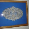 An antique doily in a frame.