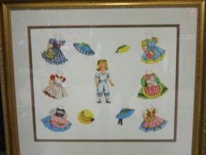 Gold frame with paper doll and doll clothing.