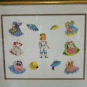 Gold frame with paper doll and doll clothing.