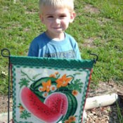 Small boy standing behind a garden flag.