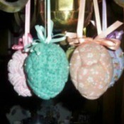 Easter eggs with a quilted appearance hanging from a chandelier.
