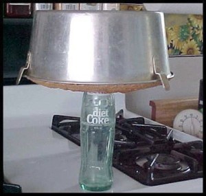 A bundt cake pan upside down on a soda bottle.