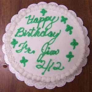 A white cake with green writing and shamrocks.