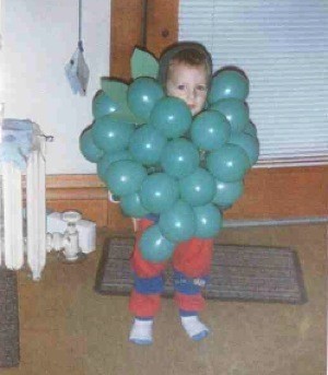 Little boy dressed as a bunch of grapes.