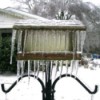 Birdfeeder covered in ice and icicles.
