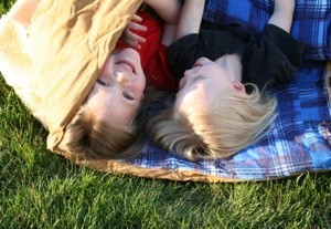 Kids in a sleeping bag on the lawn.