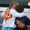 Two kids wearing jackets with an orange and white clown fish painted on them.