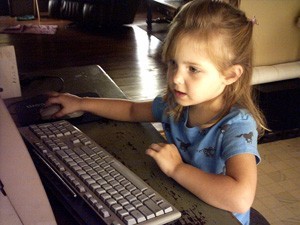 Young girl using computer mouse.