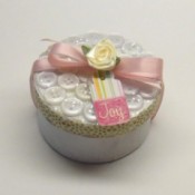 Round box decorated with buttons and pink ribbon.