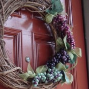 A grapevine wreath decorated with artificial grapes and leaves.