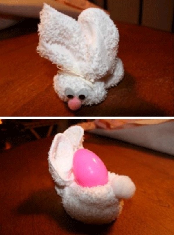 White towel folded into an Easter bunny with plastic egg in pouch.