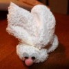 White towel folded into an Easter bunny with plastic egg in pouch.