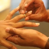 A wedding ring being placed on the ring finger.