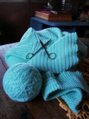 A knitted item with a ball of yarn being unraveled from it.