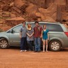 A family posing for a photo in front of a car.