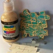 Metallic glue decorating puzzle pieces to make a decorative pin.