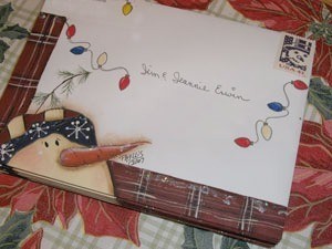 A Christmas card envelope with hand drawn snowman and string of lights.