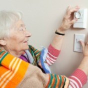 A woman adjust her heat thermostat to save money.