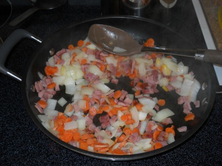 Frying ham, carrots, and onion.