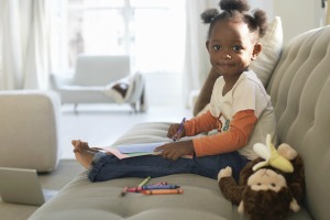 Girl drawing with crayons on microfiber.