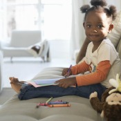 Girl drawing with crayons on microfiber.