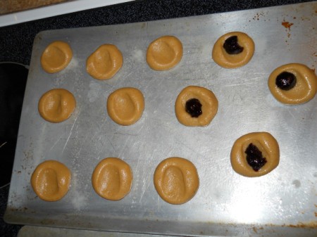 Cookie dough on sheet, adding jam.