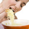 A woman eating a frugal bowl or ramen noodles.