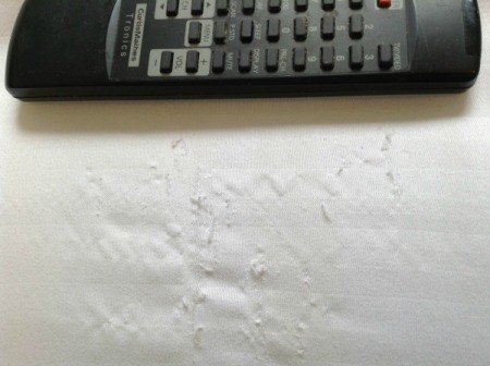 Damage to sheets next to remote for scale.