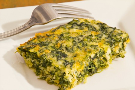 Piece of quiche from a large quiche baked in a casserole dish.