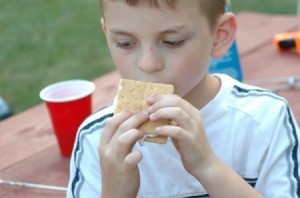 A child eating smores at a camp site.