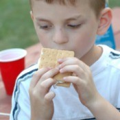 A child eating smores at a camp site.
