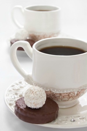 Coffee being served at a wedding in a white cup with a chocolate candy.