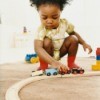 A young girl playing with a toy train.