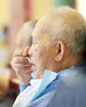 Elderly man wearing a bib while eating.