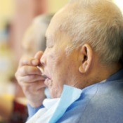 Elderly man wearing a bib while eating.