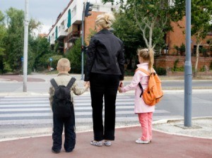 A mom and two kids crossing the street.