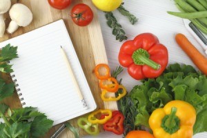 Writing a cookbook, in the kitchen. Photo of a notepad surrounded by vegetables.