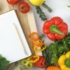 Writing a cookbook, in the kitchen. Photo of a notepad surrounded by vegetables.