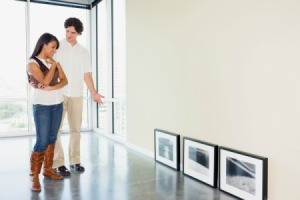 A couple looking at framed artwork in their apartment.