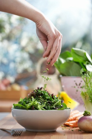 Woman Sprinkling Herbs on Her Summer Salad
