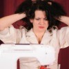 A woman getting frustrated with her sewing machine.