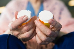 Old woman holding prescription drug bottles.