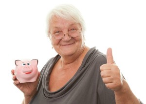 An older woman holding a piggy bank and giving a thumbs up.