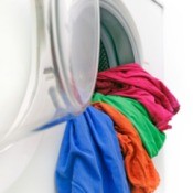 Colorful clothing hanging out of a washing machine.